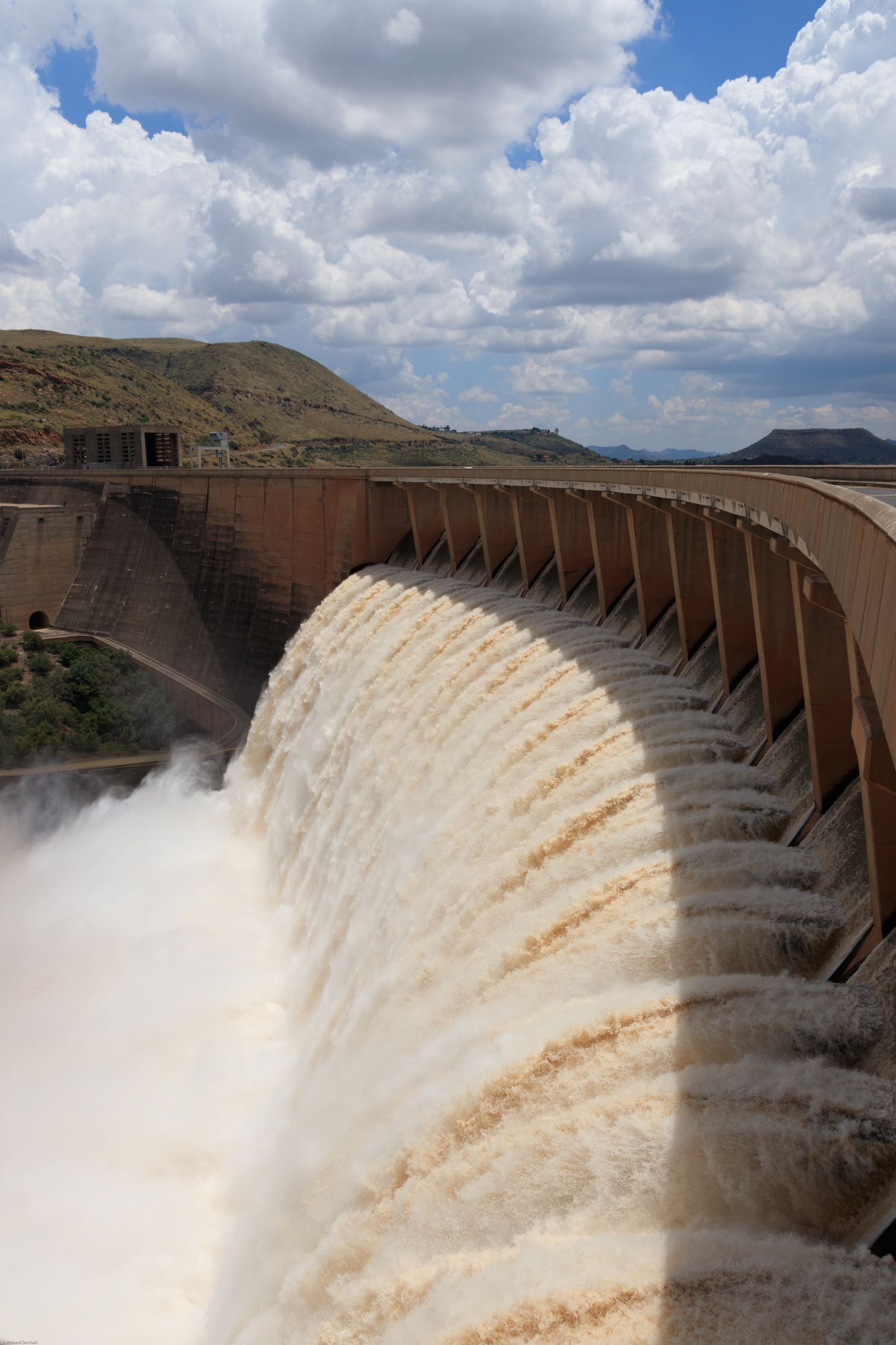 Water cascading over a hydroelectric dam spillway under a cloudy sky