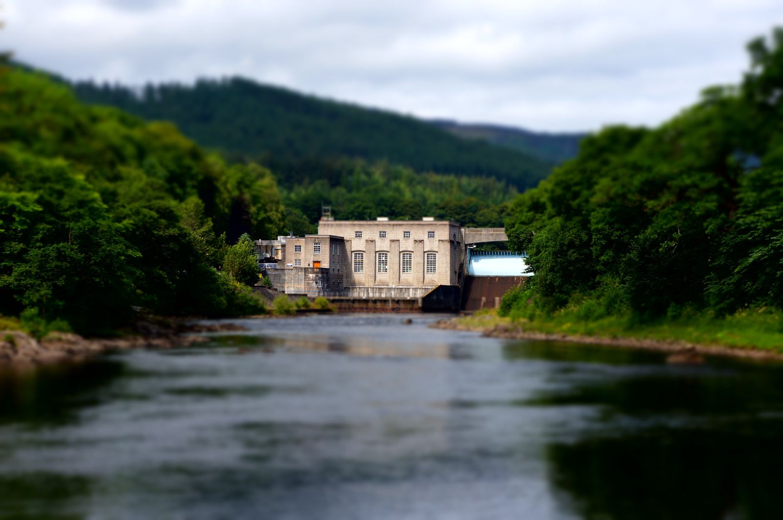 Hydroelectric powerhouse in a forested setting with river in front
